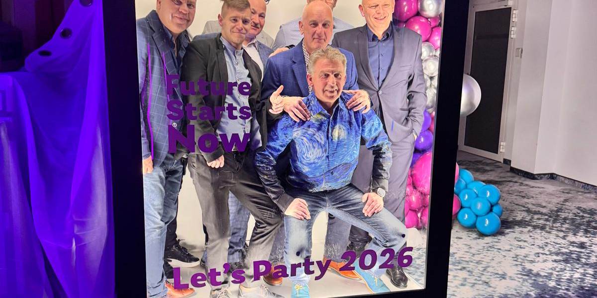 Grupa gości pozuje w wielkoformatowej okładce Magazine PhotoBox „Let’s Party 2026” na firmowym evencie